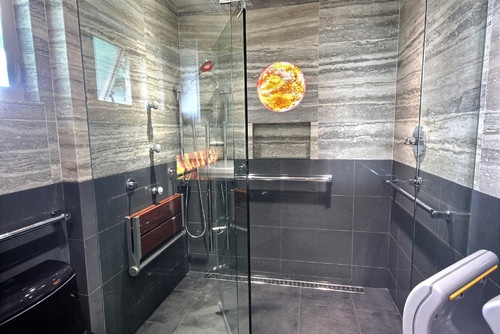 A gorgeous marble tile and gray glass handicap bathroom