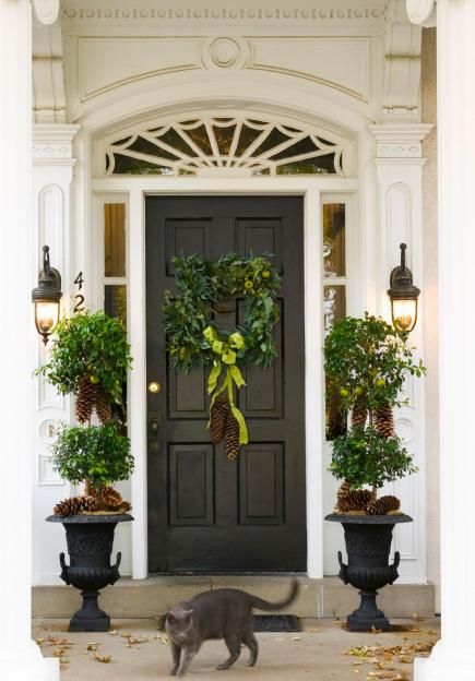 Black door entry with pine cone topiaries via Midwest Living